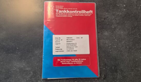 Rot-blaues Tankkontrollheft auf Betonboden – wichtiges Dokument für Heizöltank-Besitzer im Kanton Zürich